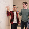 Two men in front of white board