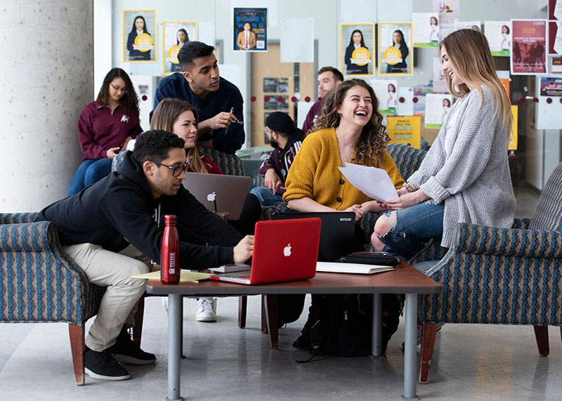 students in the Desmarais student lounge studying and laughing